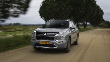 Mitsubishi Outlander Phev (2025) fahrend von vorn fotografiert in einem hellen Grau lackiert