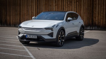Schräg von vorn vor einer Holzwand fotografierter weißer Polestar 3