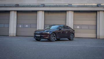 auberginefarbener Volvo ES90 steht vor Hallentoren und wurde schräg von vorn fotografiert