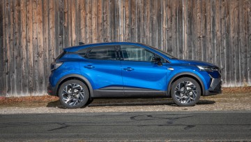 Renault Captur EDC 160 Esprit Alpine in blau in der Seitenansicht stehend vor einer Holzhuette