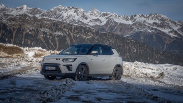 Weißer KGM Tivoli 4x4 steht auf einer Straße in der Abendsonne, von schräg vorn fotografiert