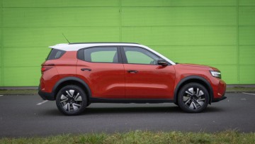 Orangefarbener Opel Frontera seitlich vor grüner Wand fotografiert