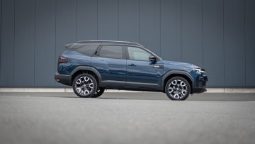Dacia Bigster in der Seitensicht stehend vor grauer Hauswand