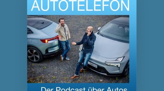 Die Redakteure Paul-Janosch Ersing und Michael Blumenstein telefonieren nebeneinander, jeweils an einen Polestar 4 angelehnt.