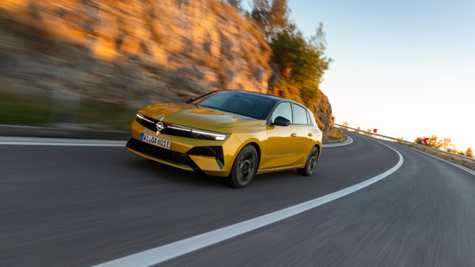 Gelber Opel Astra fahrend vor Steinwand von vorn fotografiert
