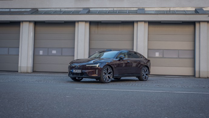 auberginefarbener Volvo ES90 steht vor Hallentoren und wurde schräg von vorn fotografiert