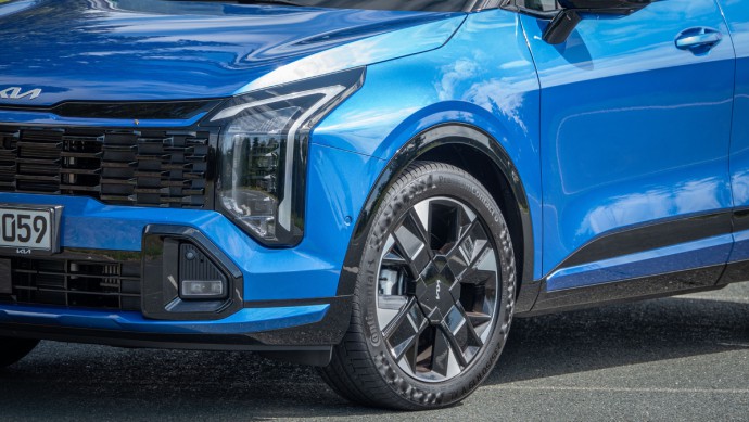 19-Zoll-Felge und Teil der neuen Front des 2026er-Faceliftmodells des Kia Sportage in Flame Blue Metallic