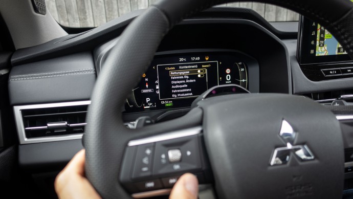 Foto vom Daumen auf den Lenkradtasten zum Deaktivieren einiger Assistenzsysteme im Mitsubishi Outlander 2025
