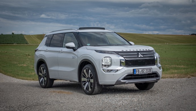 Mitsubishi Outlander vor einer großen grünen Wiese auf Kies stehend, Outlander in weiß lackiert
