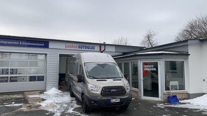 Ford Transit von Junited Autoglas vor einem Werkstatttor