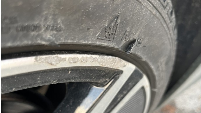 Kleine Beschädigung an der Reifenflanke eines Autoreifens, hervorgerufen durch den Kontakt mit der Bordsteinkante
