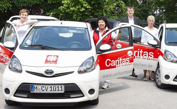 Strahlend: Die Mitarbeiter der Caritas München und Freising freuen sich über ihre Toyota Aygo, die eine vorzeigbare CO2-Bilanz aufweisen.