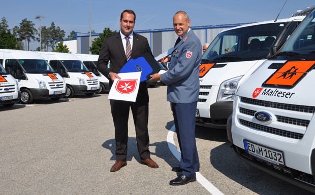 Darius Prudlo (li, Großkundenbetreuer bei Auto Fiegl, Schwabach) übergibt Michael Bauer (Leiter Fahrdienst bei den Maltesern Bayern/Thüringen) den symbolischen Fahrzeugschlüssel. 