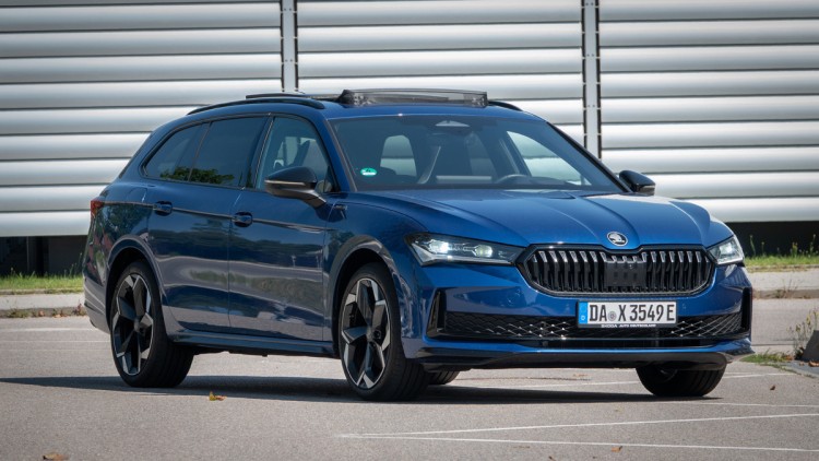 Vor einer silbernen Metallwand schräg von vor fotografierter Skoda Superb iV.