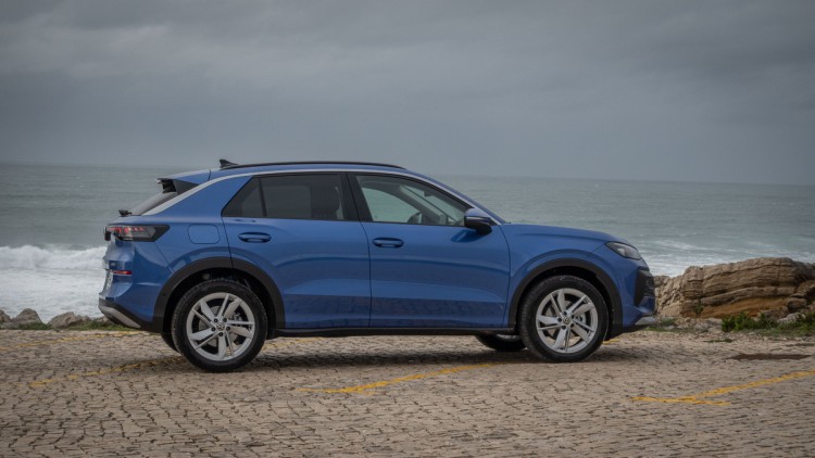 In der Seitensicht fotografierter VW T-Roc, stehend vor dem aufbrausenden Atlantik in Portugal