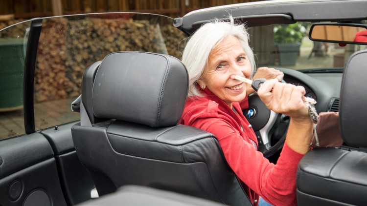 Dame im Cabrio mit Schlüssel in der Hand nach hinten schauend