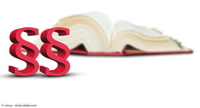 Paragraphen-Symbole im Vordergrund, im Hintergrund ein aufgeschlagenes Gesetzbuch.