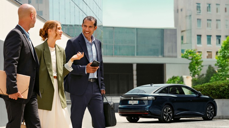 Better with every move: Ayvens startet in Deutschland Kollegen unterhalten sich auf dem Firmenparkplatz