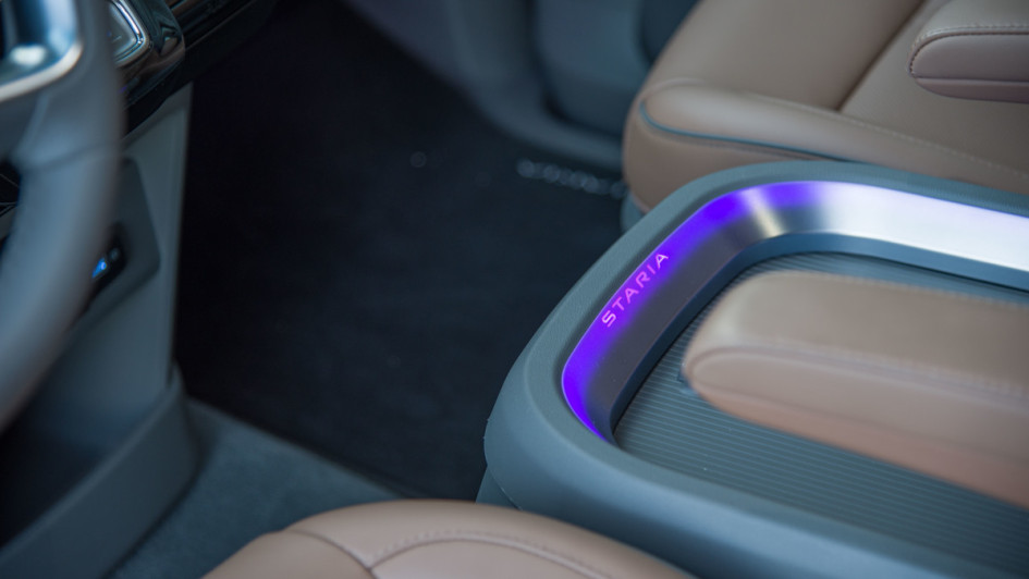 Hyundai Staria LED-Beleuchtung in lila an der Staubox zwischen Fahrer und Beifahrer