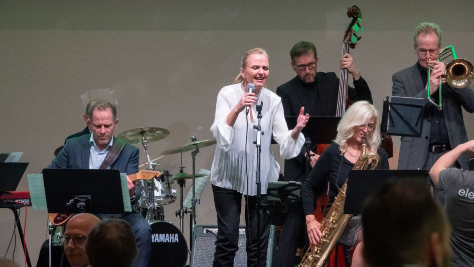 Sängerin steht auf der Bühne mit einer Big Band im Hintergrund