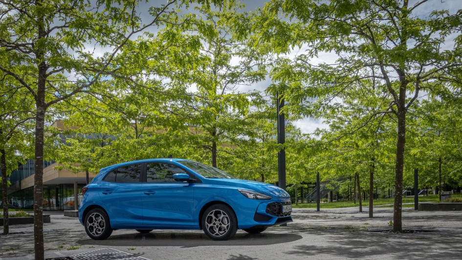 MG3 Hybrid in der Seitenansicht unter Bäumen mit grünen Laubblättern geparkt