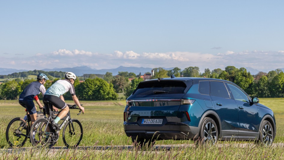 Foto des neuen Opel Grandland Hybrid von hinten aufgenommen vor einem leichten Hügel