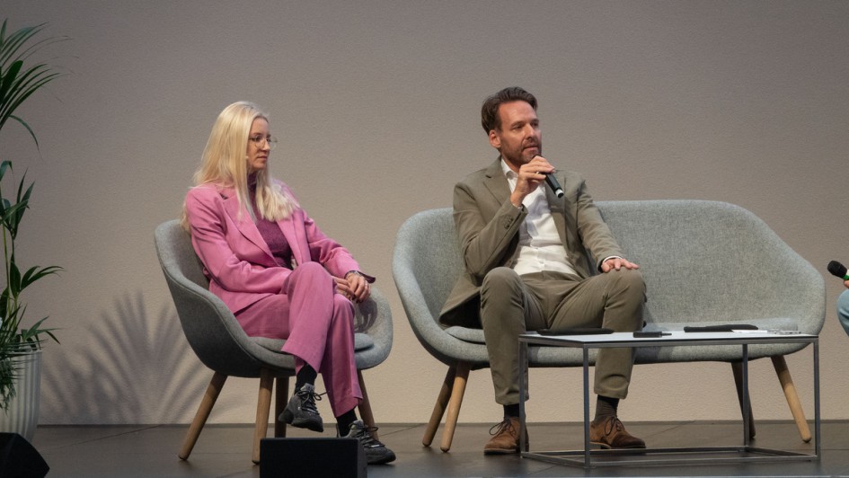 Zwei Menschen diskutieren auf einem Sofa auf der Bühne der Nakobemo