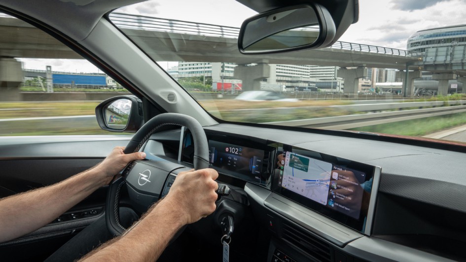 Fotoaufnahme von innen während der Fahrt in Richtung Tacho. Fahrer hat beide Hände am lenkrad.