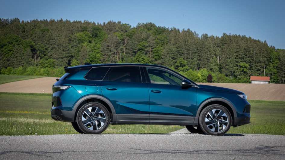 Foto des Opel Grandland Hybrid in der Seitenansicht vor einer grünen, saftigen Wiese