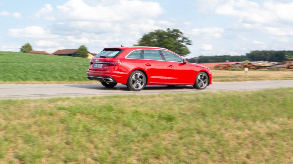 Audi A4 Avant 35 TFSI in rot fährt vor grüber Wiese auf der Landstraße