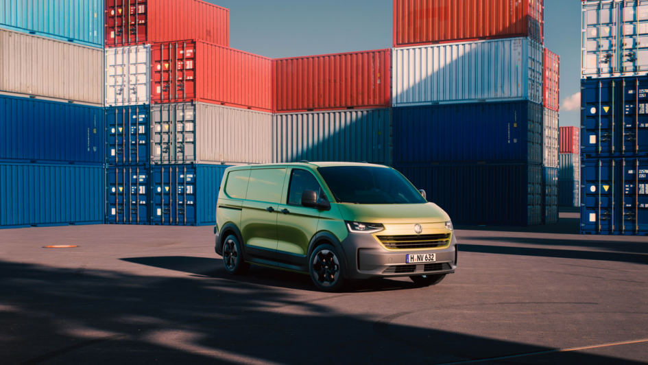 VW Transporter (2025) in Warm Green Metallic vor Containern stehend